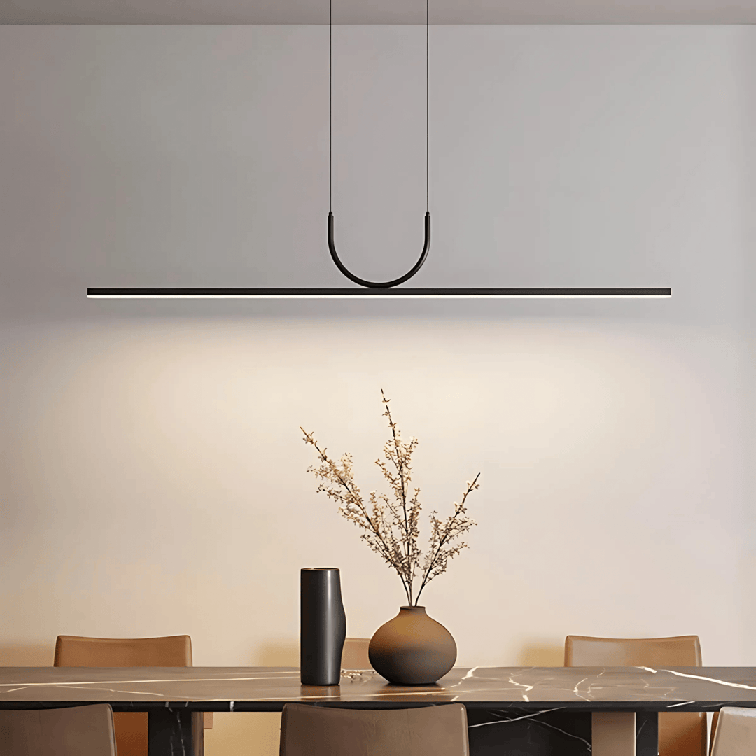 Modern black pendant light with a sleek, minimalist design hanging over a dining table.