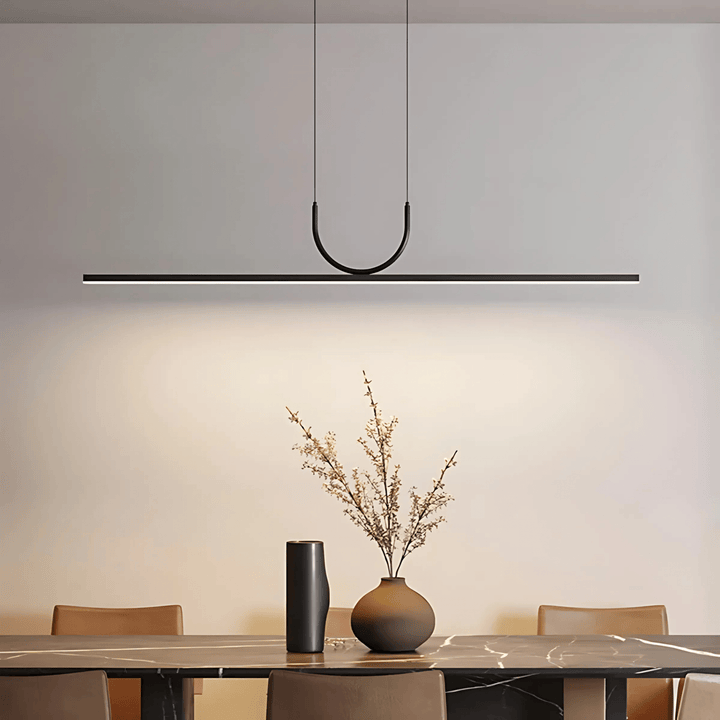 Modern black pendant light with a sleek, minimalist design hanging over a dining table.