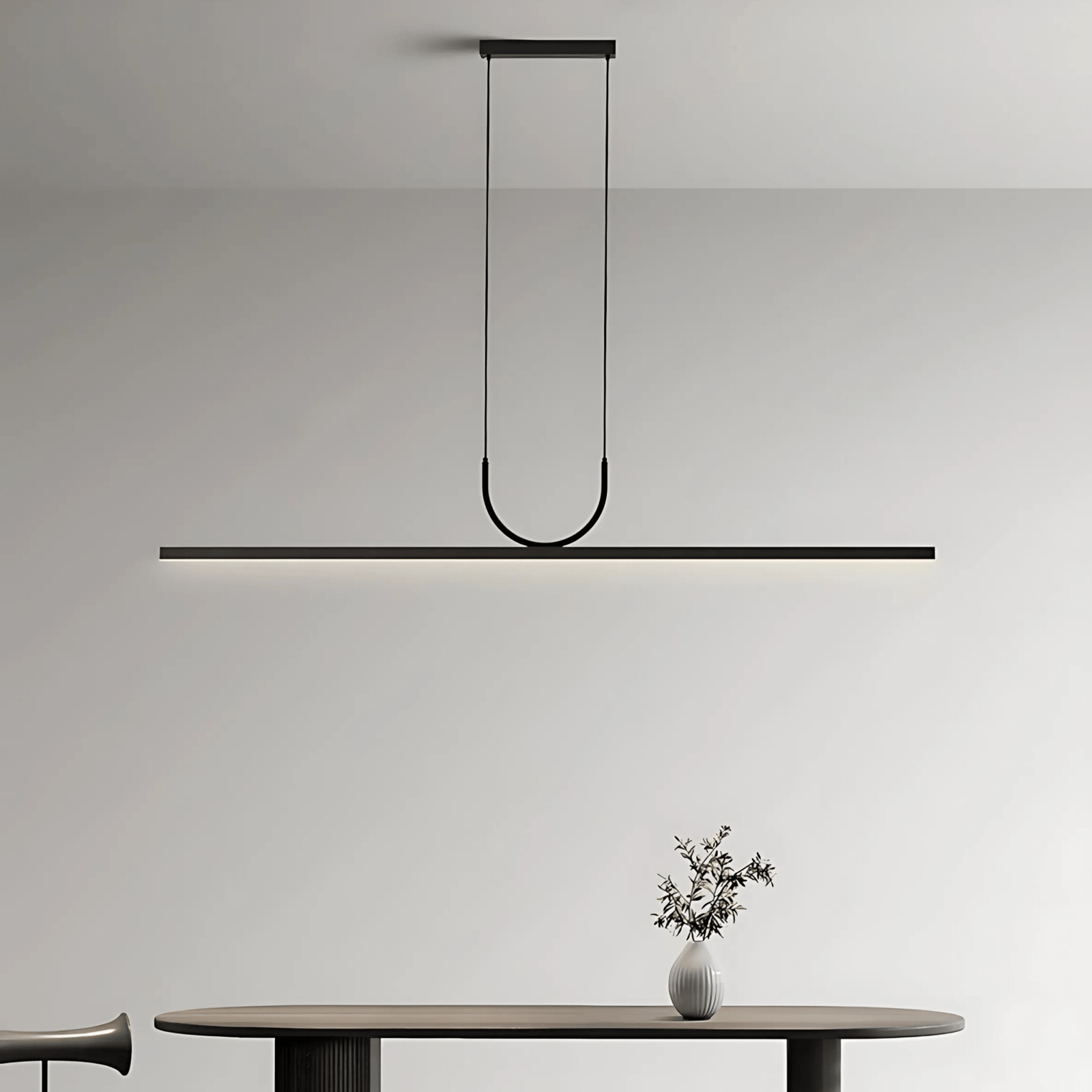 Black sleek pendant light with a U-shaped arm hanging over a dark oval table.