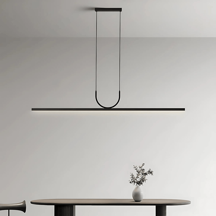 Black sleek pendant light with a U-shaped arm hanging over a dark oval table.