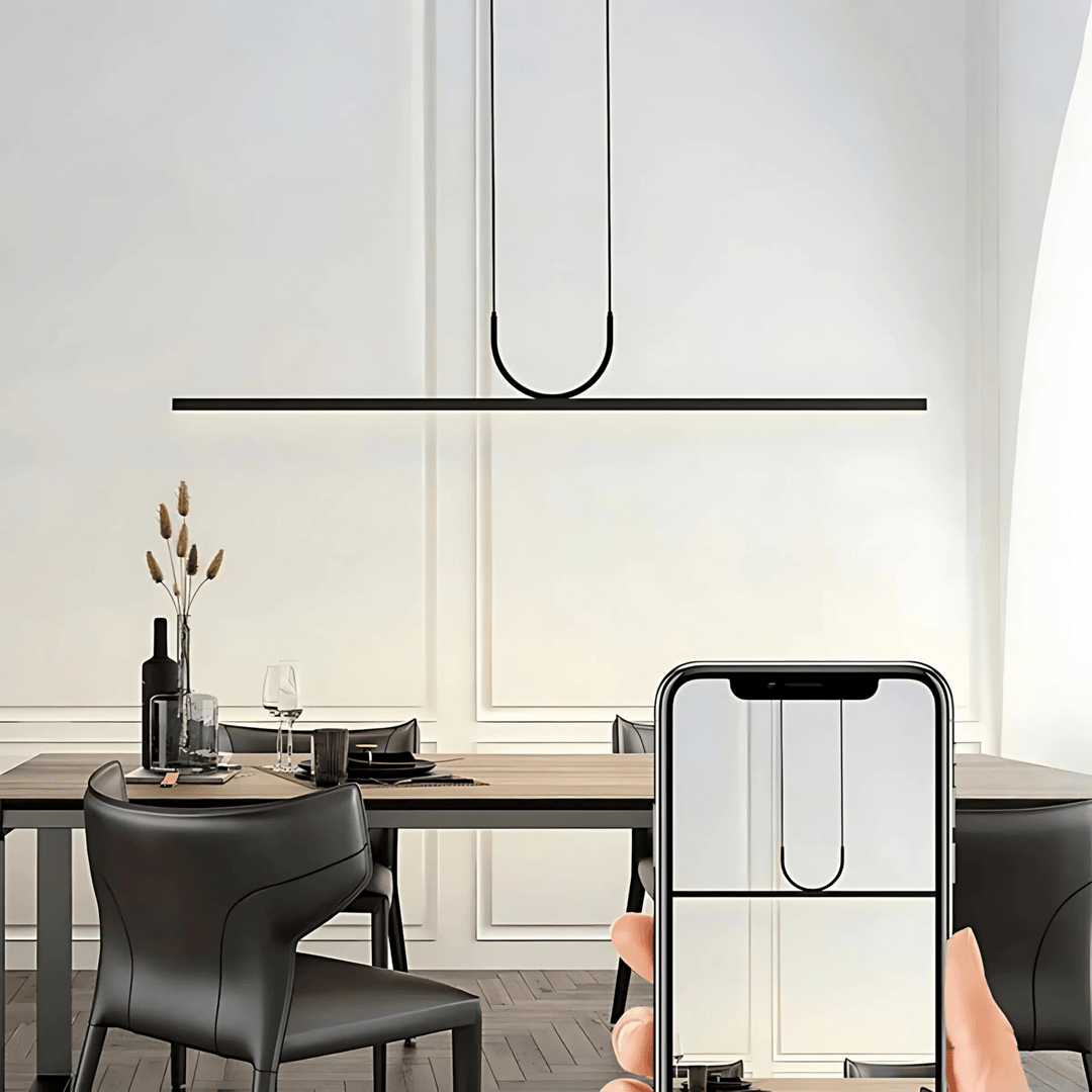 Modern black pendant light with a U-shaped element hanging above a dining table.
