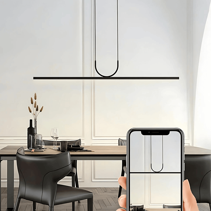 Modern black pendant light with a U-shaped element hanging above a dining table.