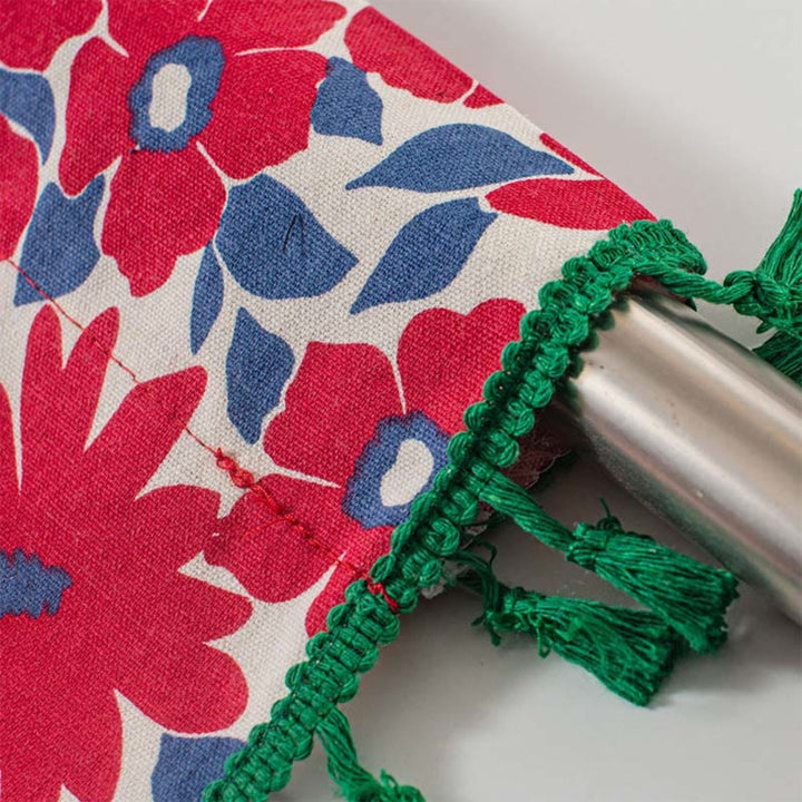 Red floral cabinet curtain with green tassel trim and a silver rod.