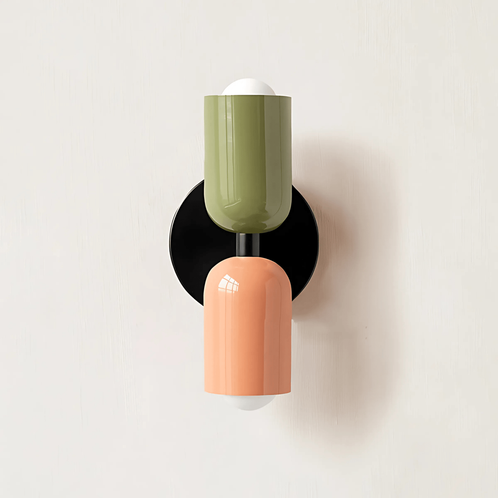 A green and peach metal wall sconce with two rounded shades and exposed bulbs.