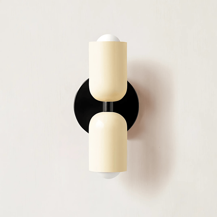 Cream-colored metal wall sconce with a black circular base and two cylindrical shades.