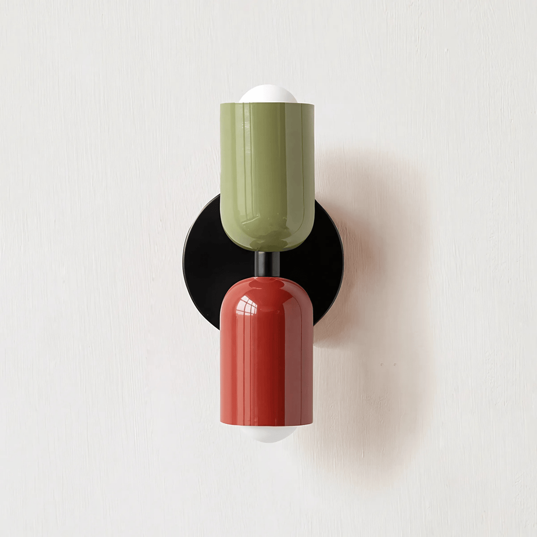 Green and red metal wall sconce with a black circular backplate and exposed bulbs.