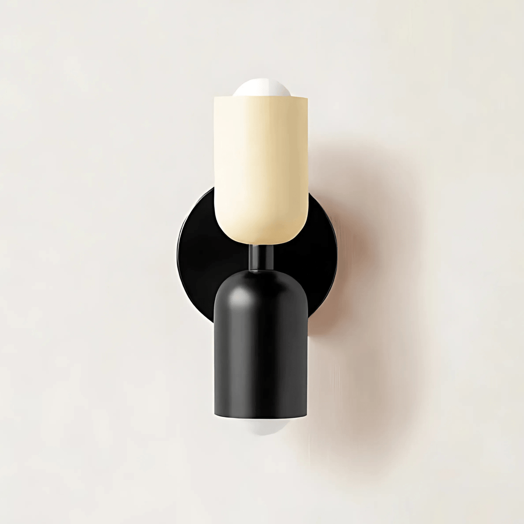Black and cream metal wall sconce with a round black base and two cylindrical shades.