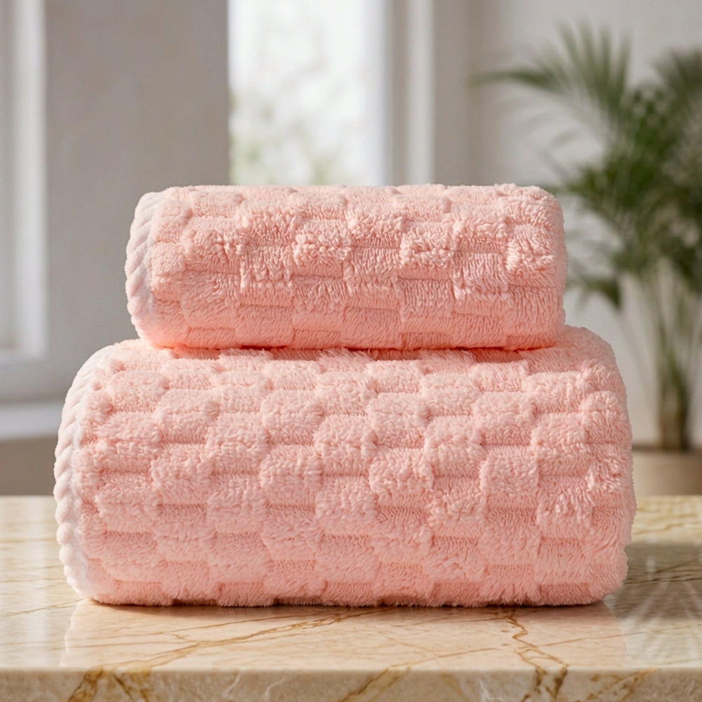 Two rolled pink fleece towels with a textured pattern stacked on a marble surface.
