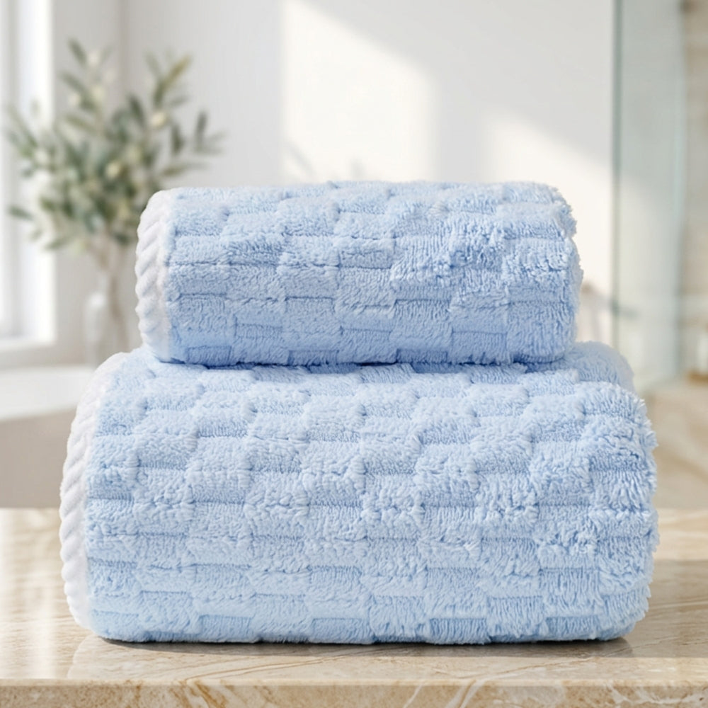 Two light blue fleece towels stacked on a marble surface.