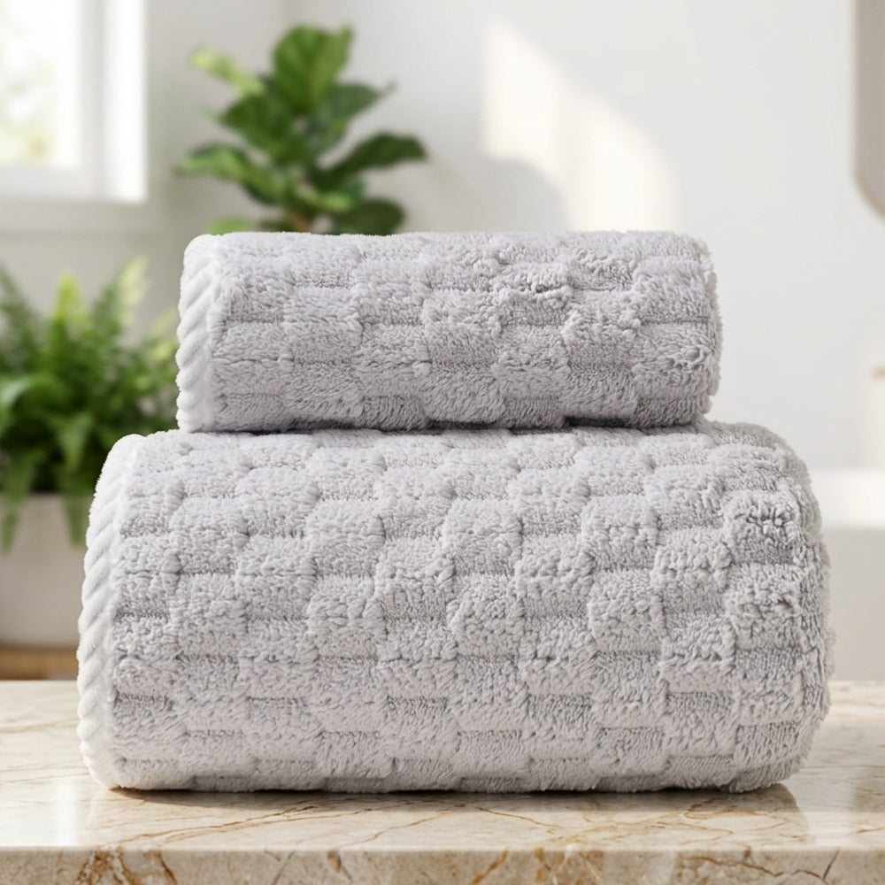 Two rolled gray fleece towels stacked on a marble countertop.