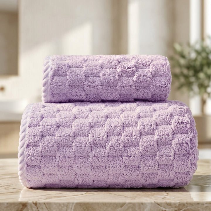 Two rolled soft fleece towels in lavender color stacked on a marble countertop.