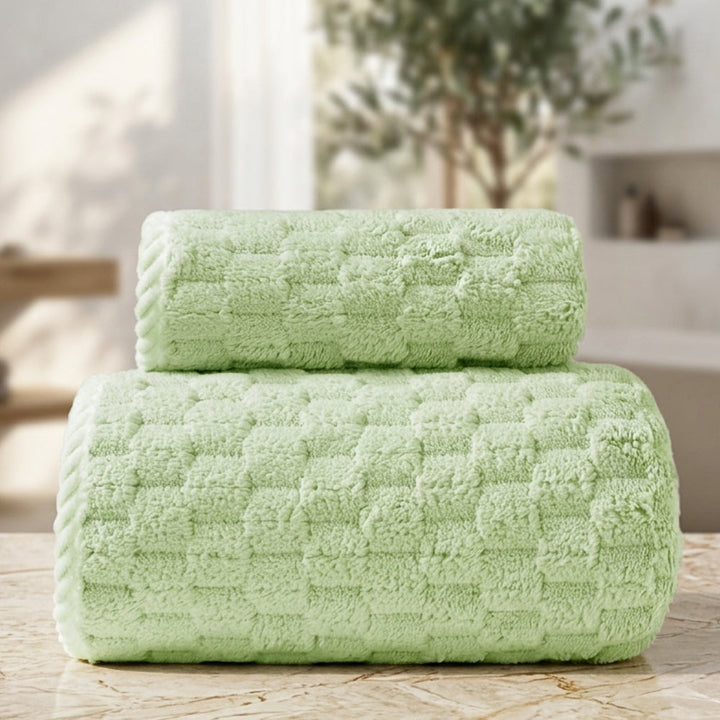 Two light green fleece towels stacked on a marble surface.