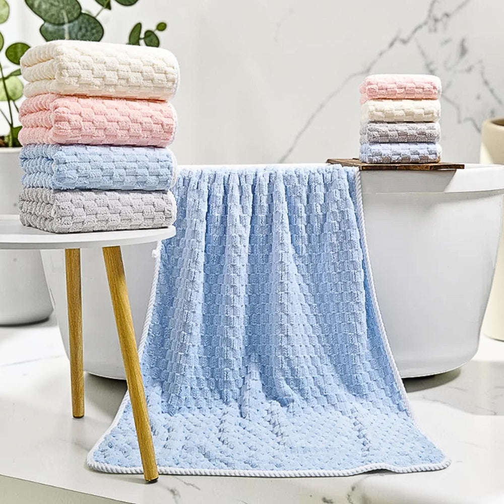 Stack of soft fleece towels in pastel colors and a large light blue towel draped over a bathtub.