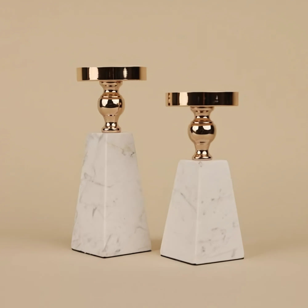 Two pyramid-shaped marble candle holders with gold accents on a neutral background.