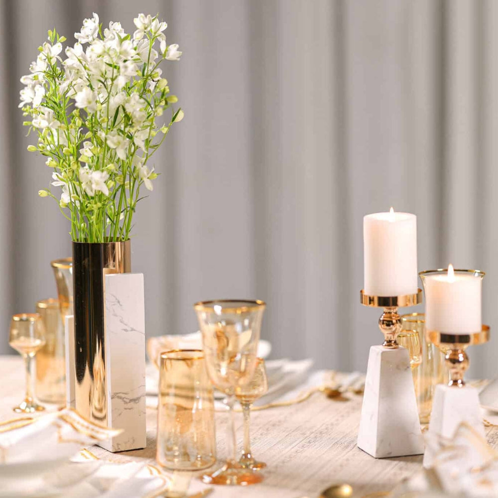 Pyramid marble candle holder with gold accents and a white pillar candle.