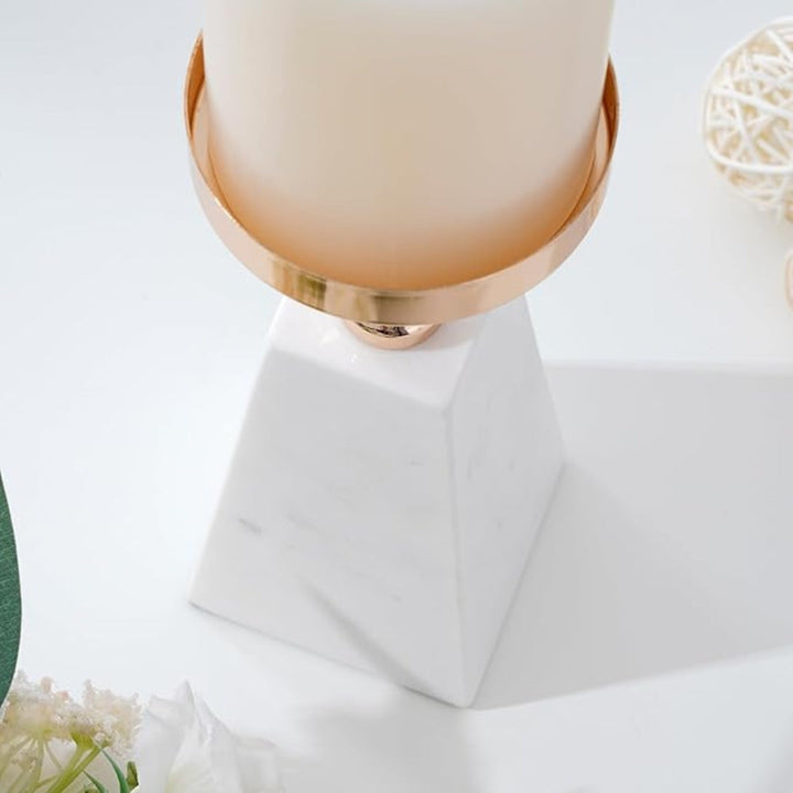 White marble pyramid candle holder with a gold rim and a cream candle.