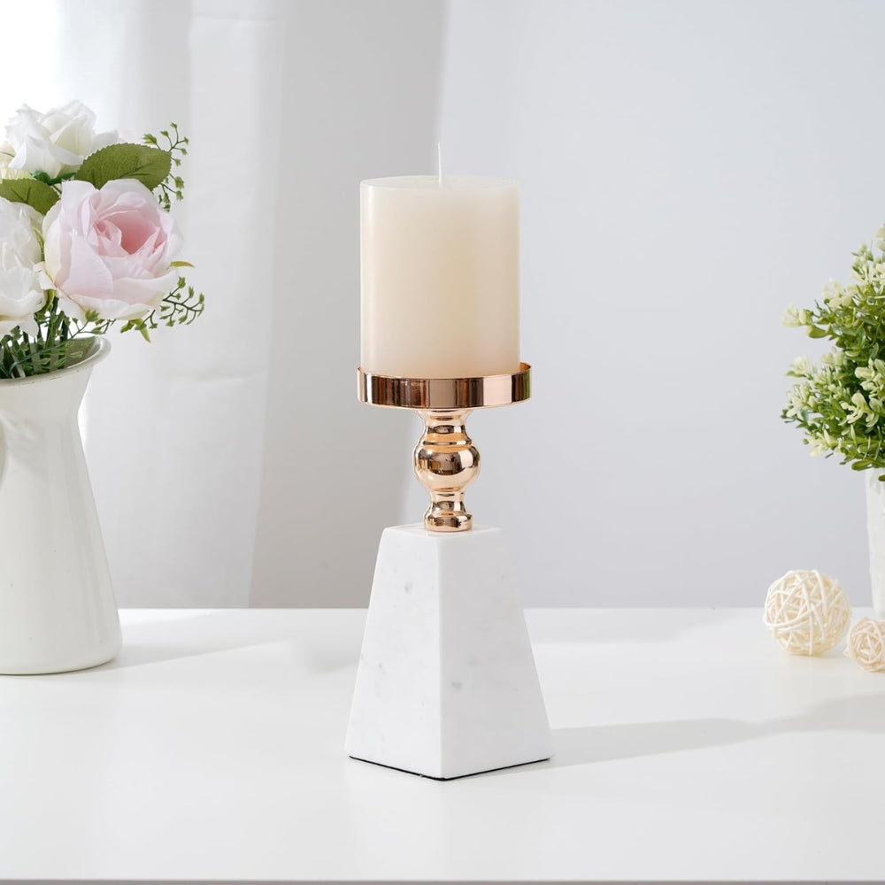White marble pyramid candle holder with a gold stem and a cream pillar candle.