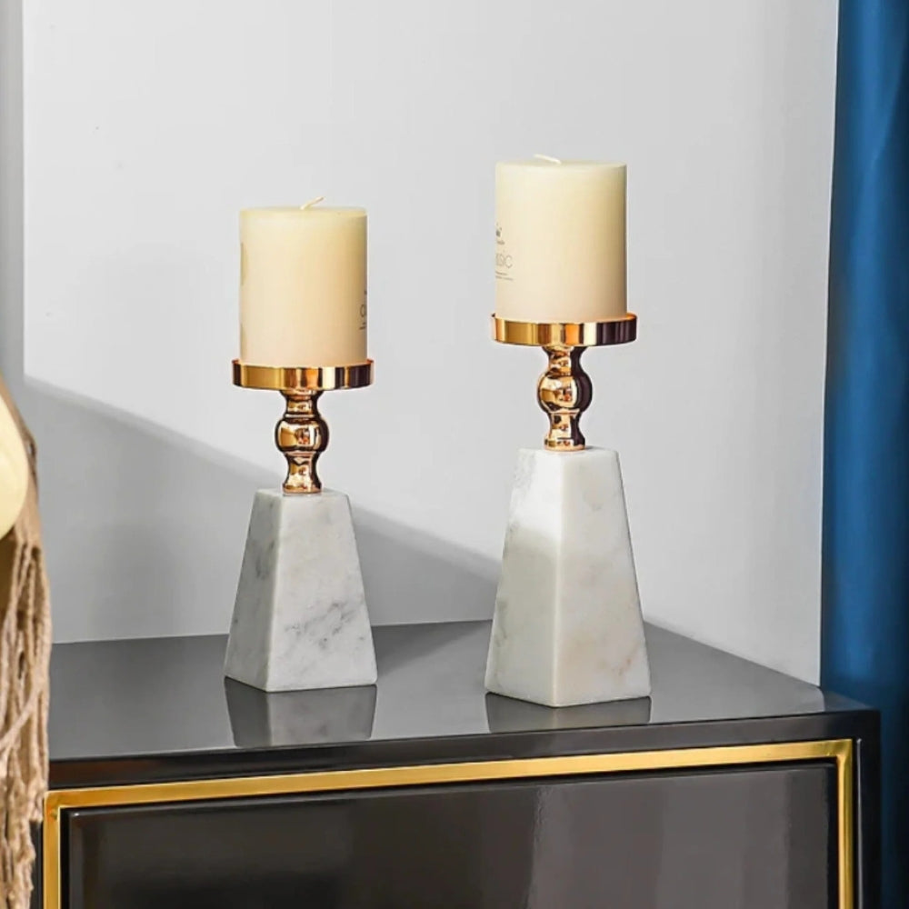 Two pyramid marble candle holders with gold accents and cream candles.