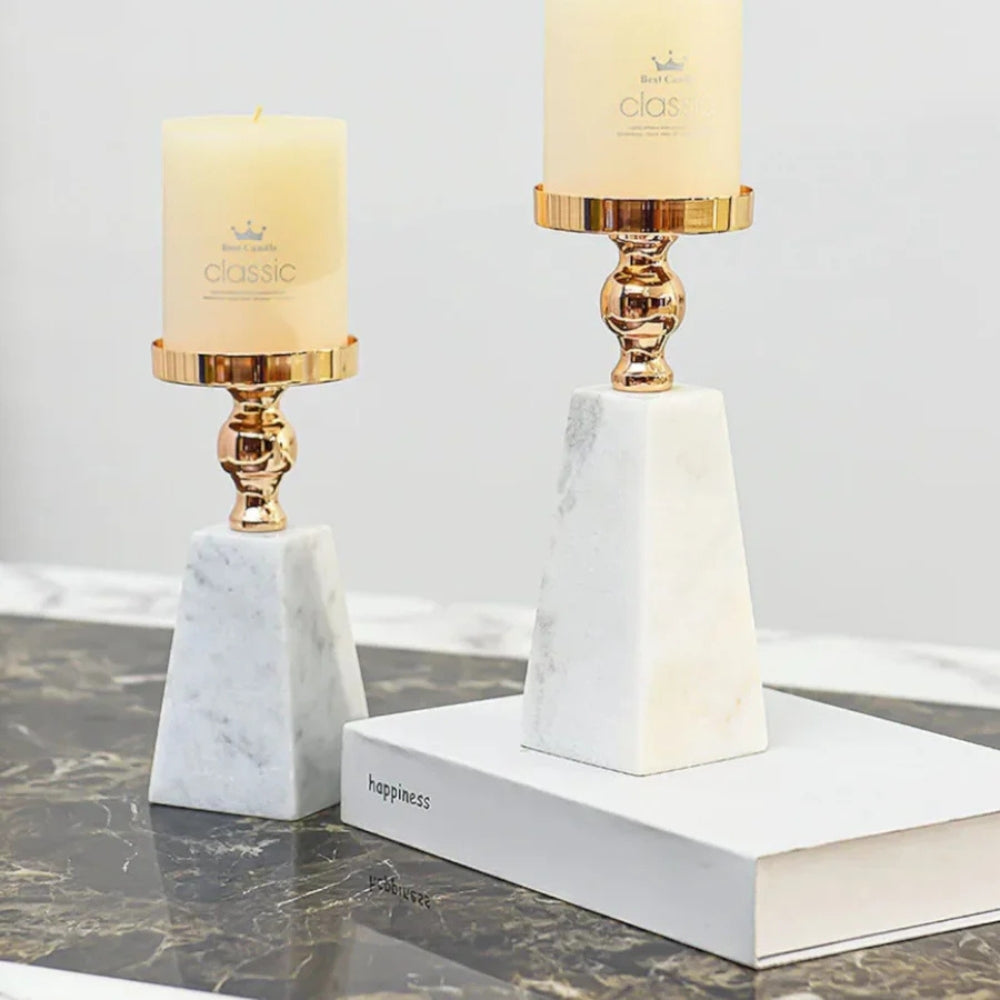 Two pyramid marble candle holders with gold accents and cream candles.