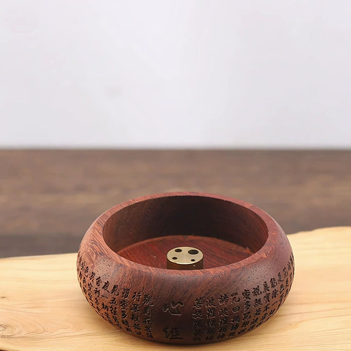 Round solid wood incense holder with a brass insert featuring multiple holes.