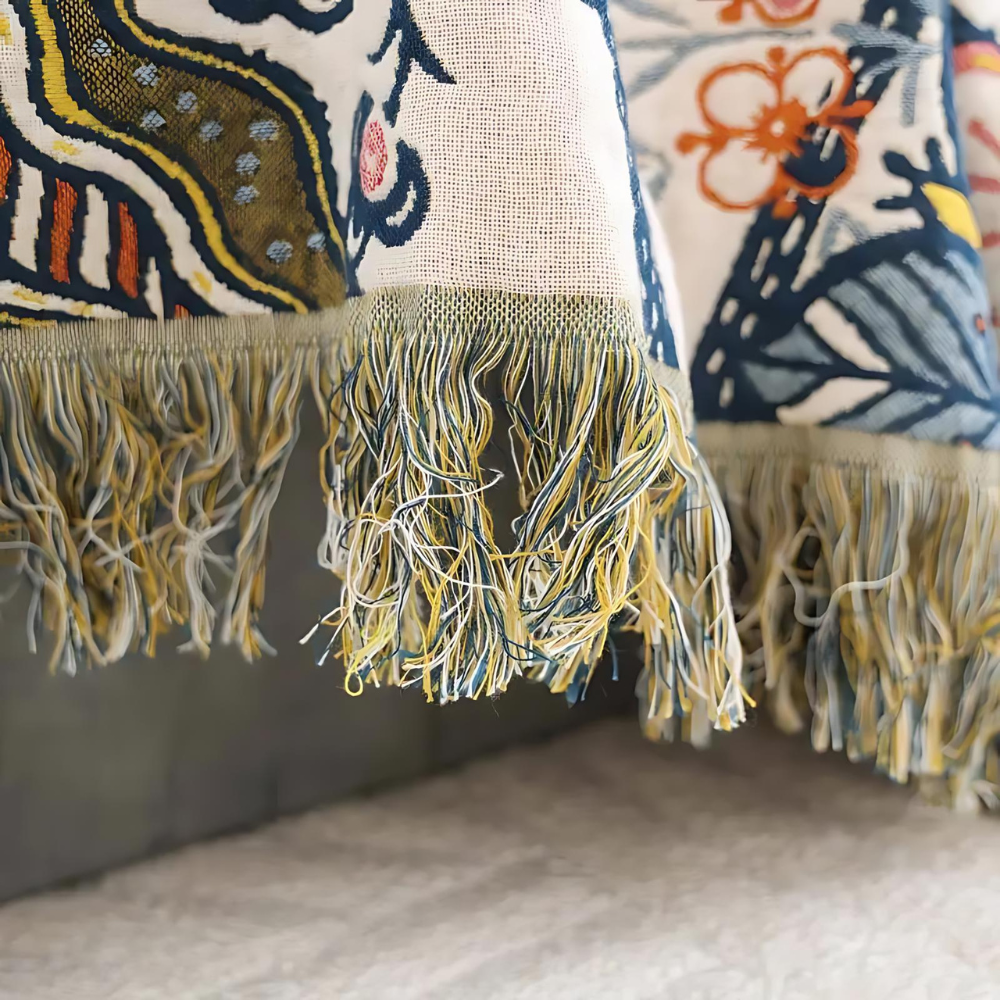 Close-up of a reversible floral cotton throw blanket with colorful tassels.