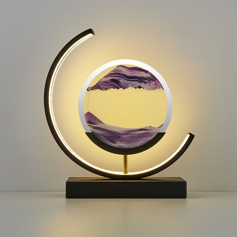 Modern black lamp with a crescent shape and a circular glass enclosure containing flowing purple sand.