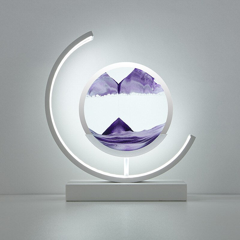 White crescent lamp base with a circular glass enclosure containing purple quicksand art.
