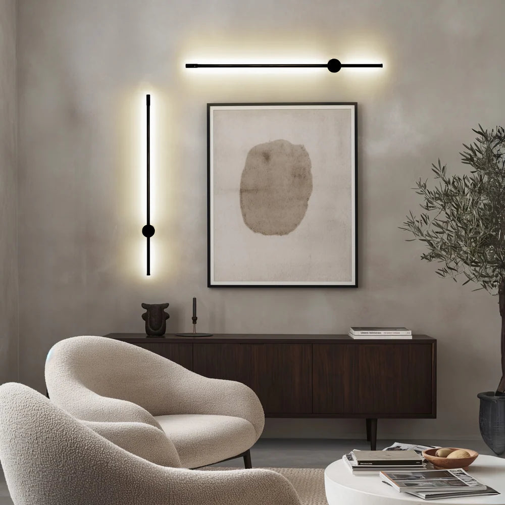 Black satin wall sconce with a sleek, modern design, illuminating a wall.
