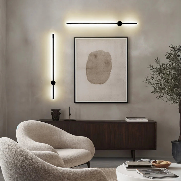 Black satin wall sconce with a sleek, modern design, illuminating a wall.