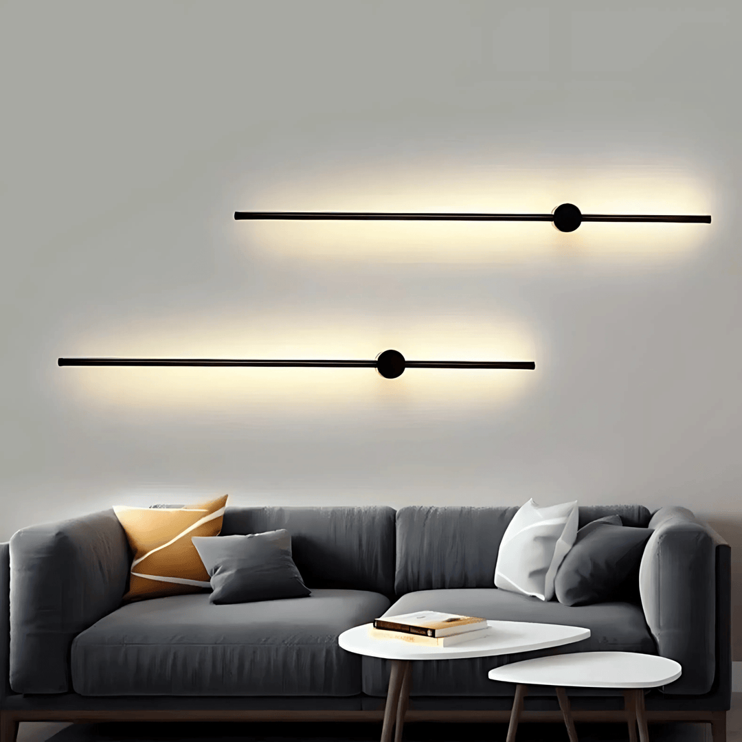Two black satin wall sconces with integrated LED lights mounted on a white wall above a grey sofa.