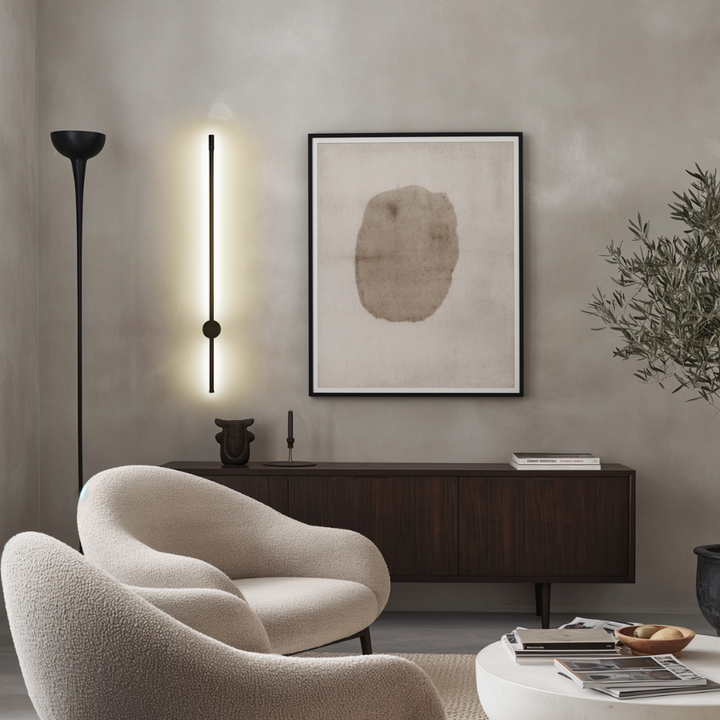 Black satin wall sconce with a sleek, modern design, illuminating a wall.