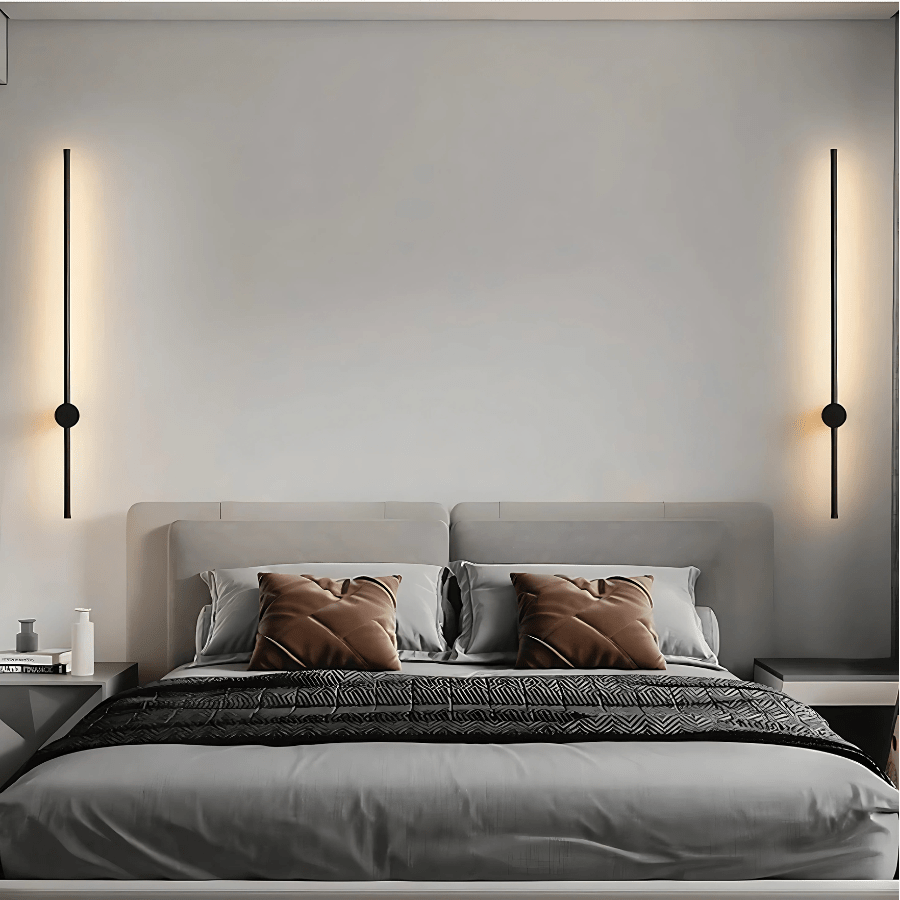 Black satin wall sconce with a sleek, modern design, illuminating a bedroom wall.