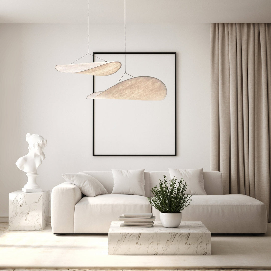 Minimalist pendant light with a sail shape, made of metal and Tyvek acrylic, hanging over a modern living room.
