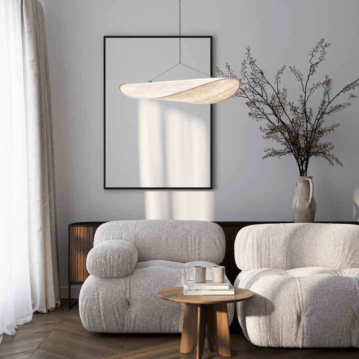 Minimalist pendant light with a sail shape, suspended above a living room setting.