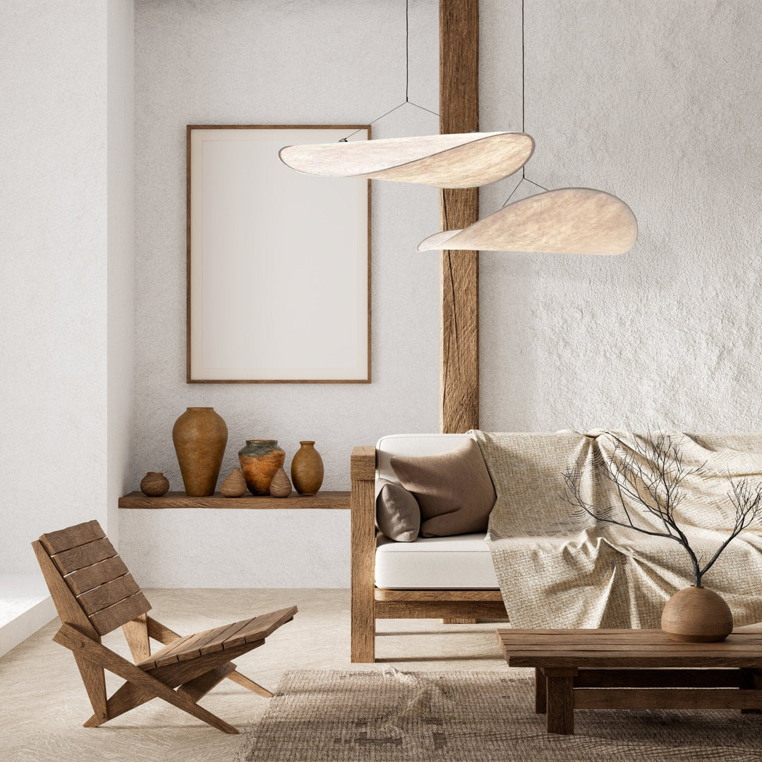 Two sail-shaped pendant lights hanging above a wooden coffee table and sofa in a minimalist living room.