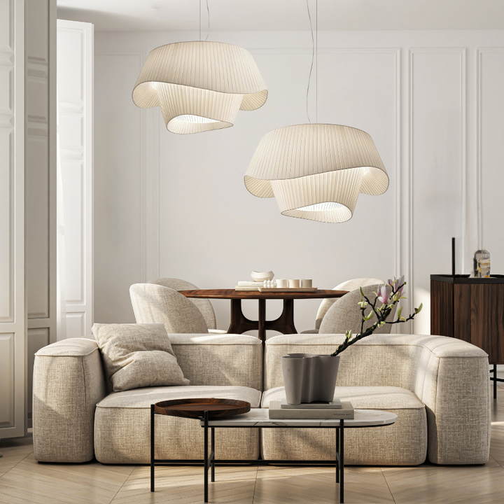 Two white acrylic pendant lights with pleated shades hang above a dining table and sofa.