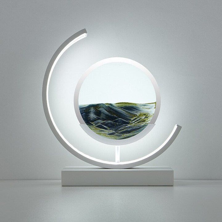 Modern white crescent lamp with a circular glass enclosure containing flowing 3D quicksand art.