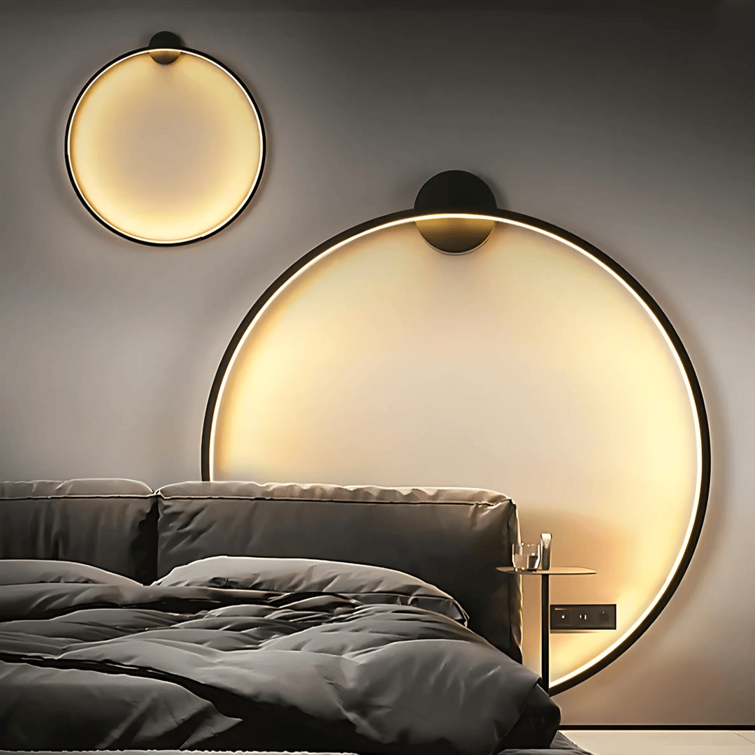 Modern circular wall sconce with warm ambient lighting above a bed.