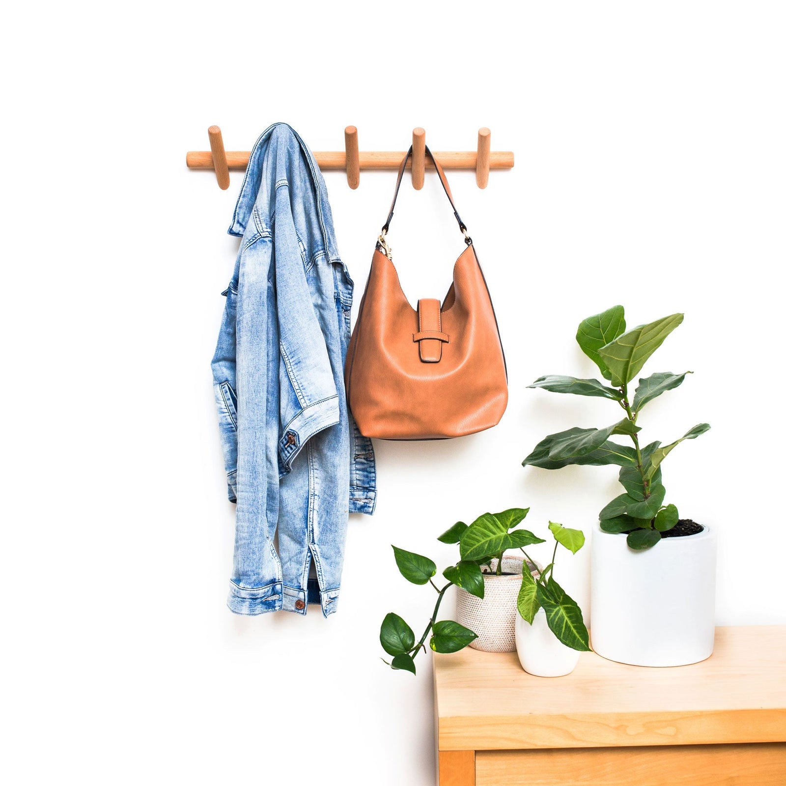 Beechwood wall coat rack with 5 hooks, holding a denim jacket and a brown leather bag.