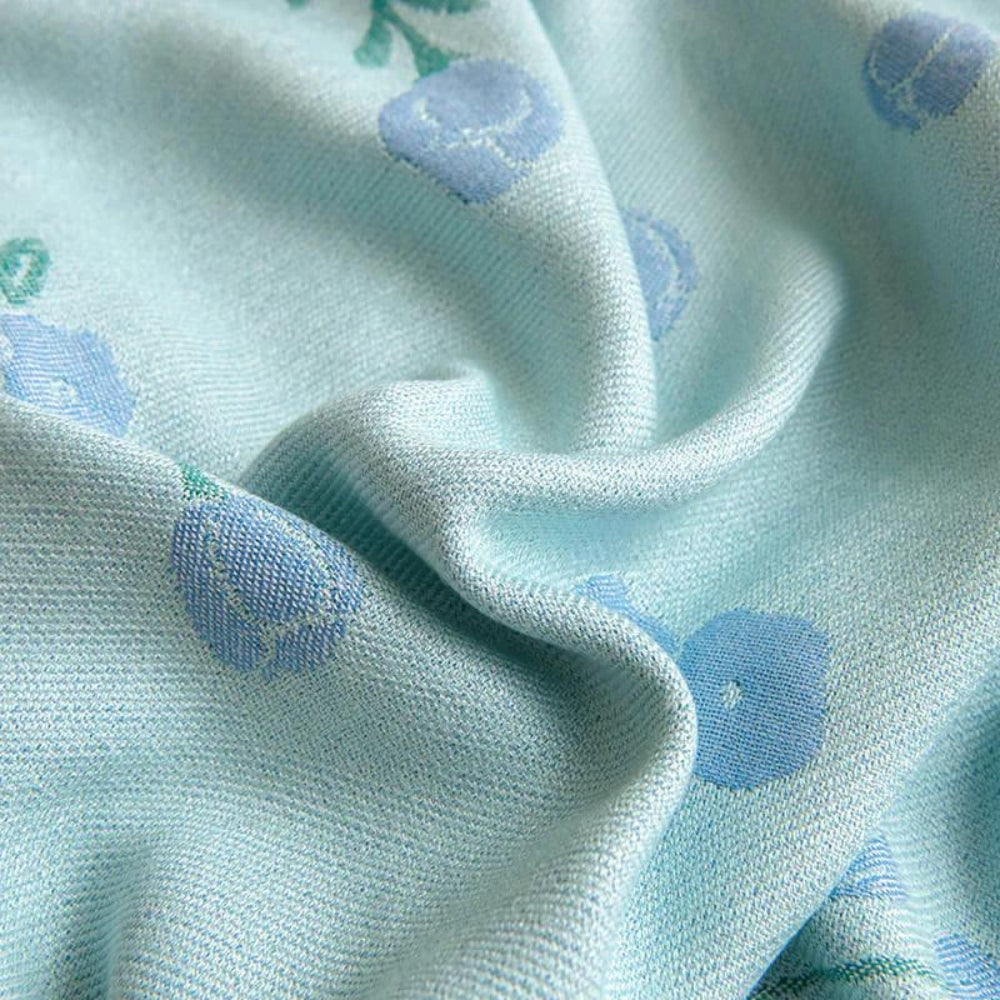 Light blue blanket with a subtle floral pattern in light blue and green.