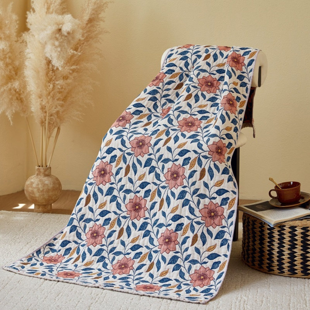 Cotton gauze bath towel with a floral leaf pattern in pink, blue, and brown on a white background.