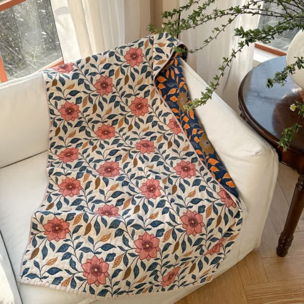Cotton gauze bath towel with a floral leaf pattern in pink, blue, and brown on a cream background.
