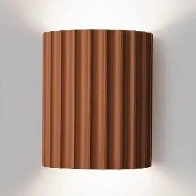 Terracotta ribbed cylindrical wall sconce with light emanating from top and bottom.