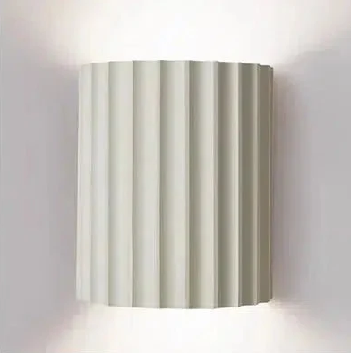 White fluted wall sconce with integrated LED lighting casting a warm glow.