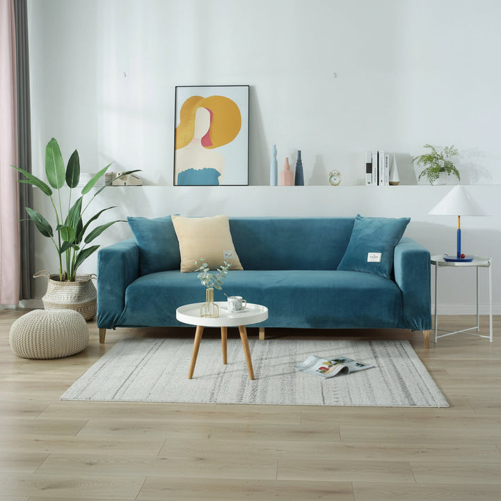 Lake blue velvet couch cover on a sofa with decorative pillows and a small coffee table.