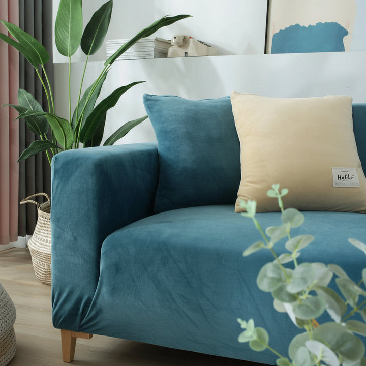 Lake blue velvet couch cover with a beige accent pillow and a plant.