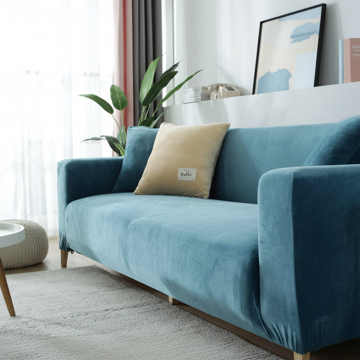 Lake blue velvet couch cover with two decorative pillows on a sofa.