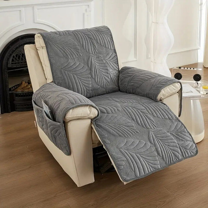 Gray quilted recliner chair cover with a leaf pattern and side pockets.
