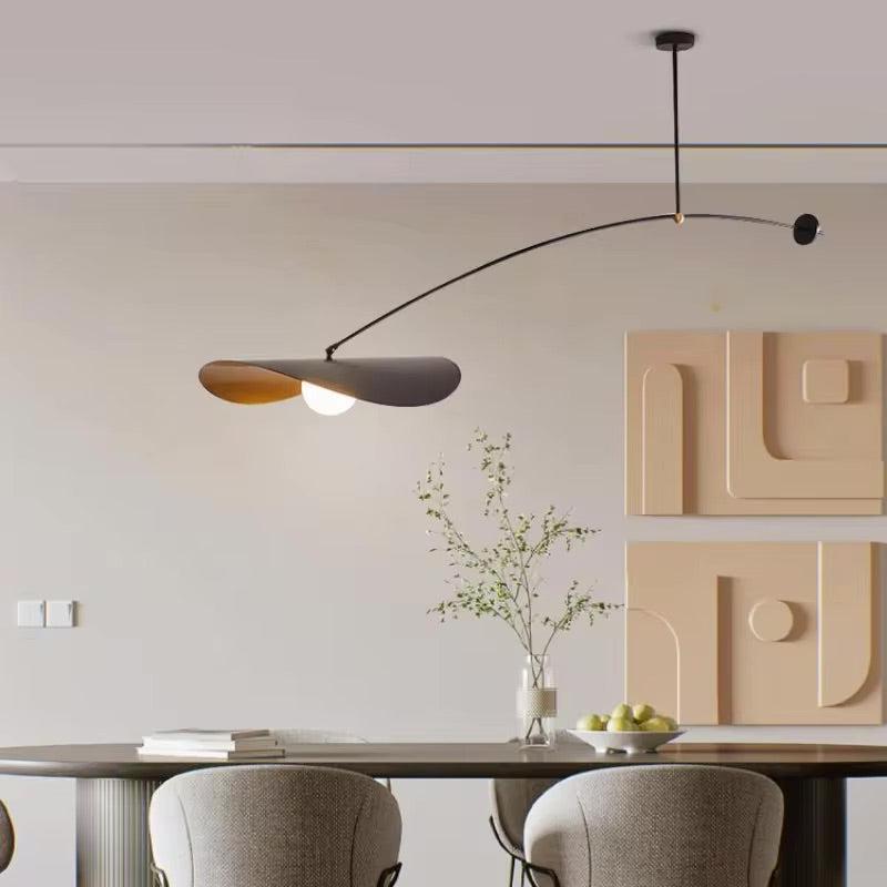 Black adjustable pendant light with a curved arm and a wide, flat shade over a dining table.