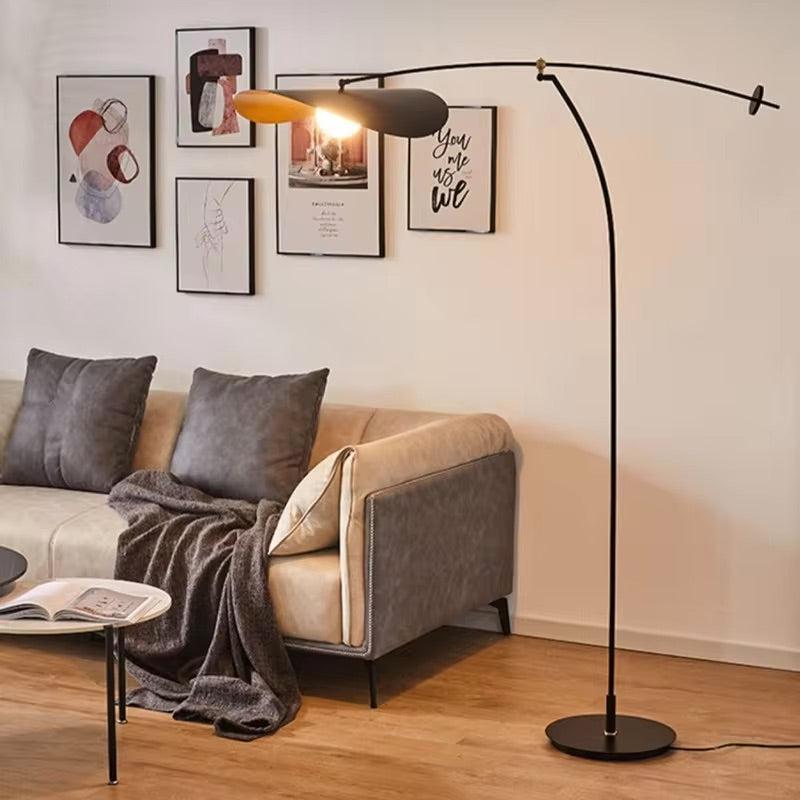 Black adjustable floor lamp with a curved arm and a light fixture over a sofa.
